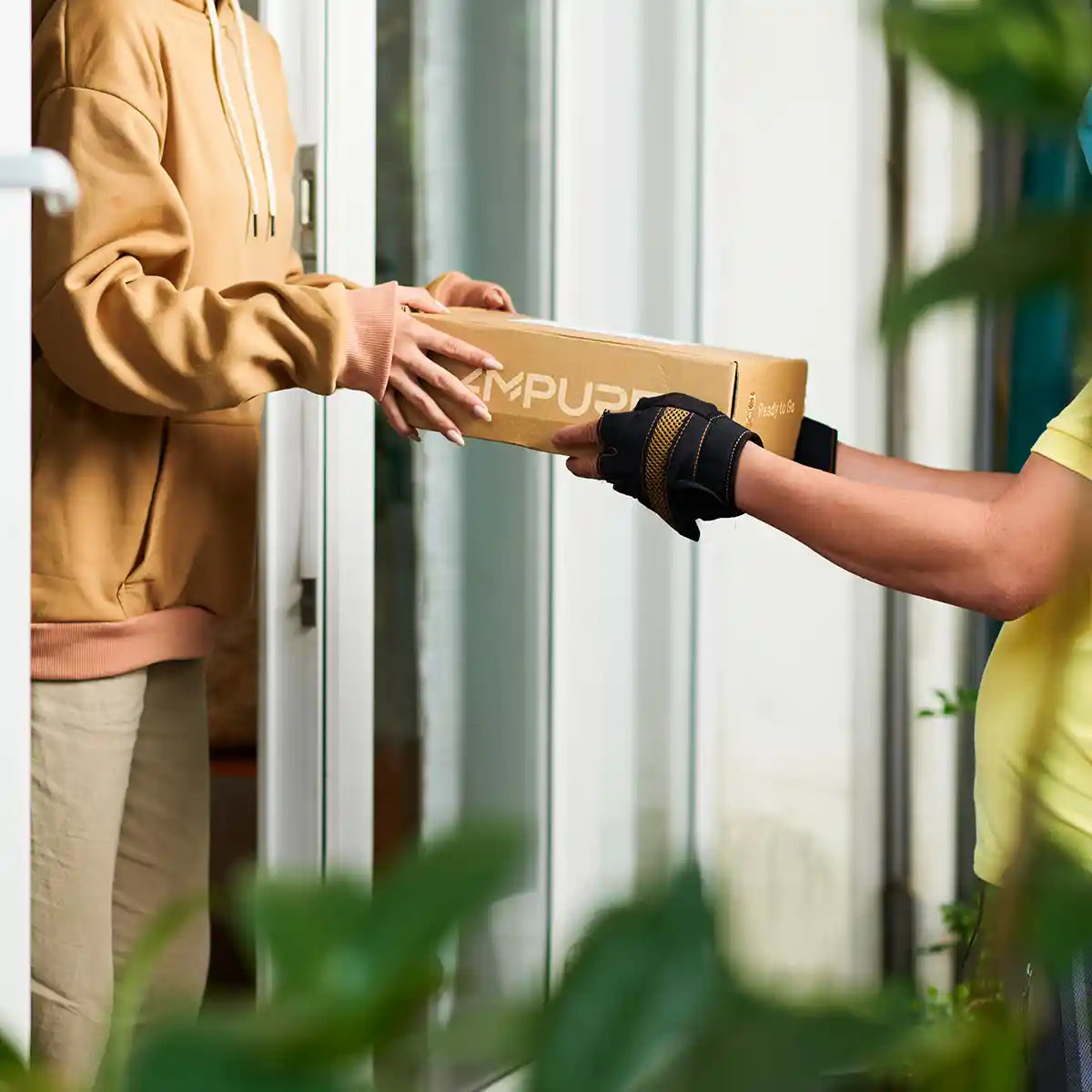 Person receiving a package from another person outside a door.