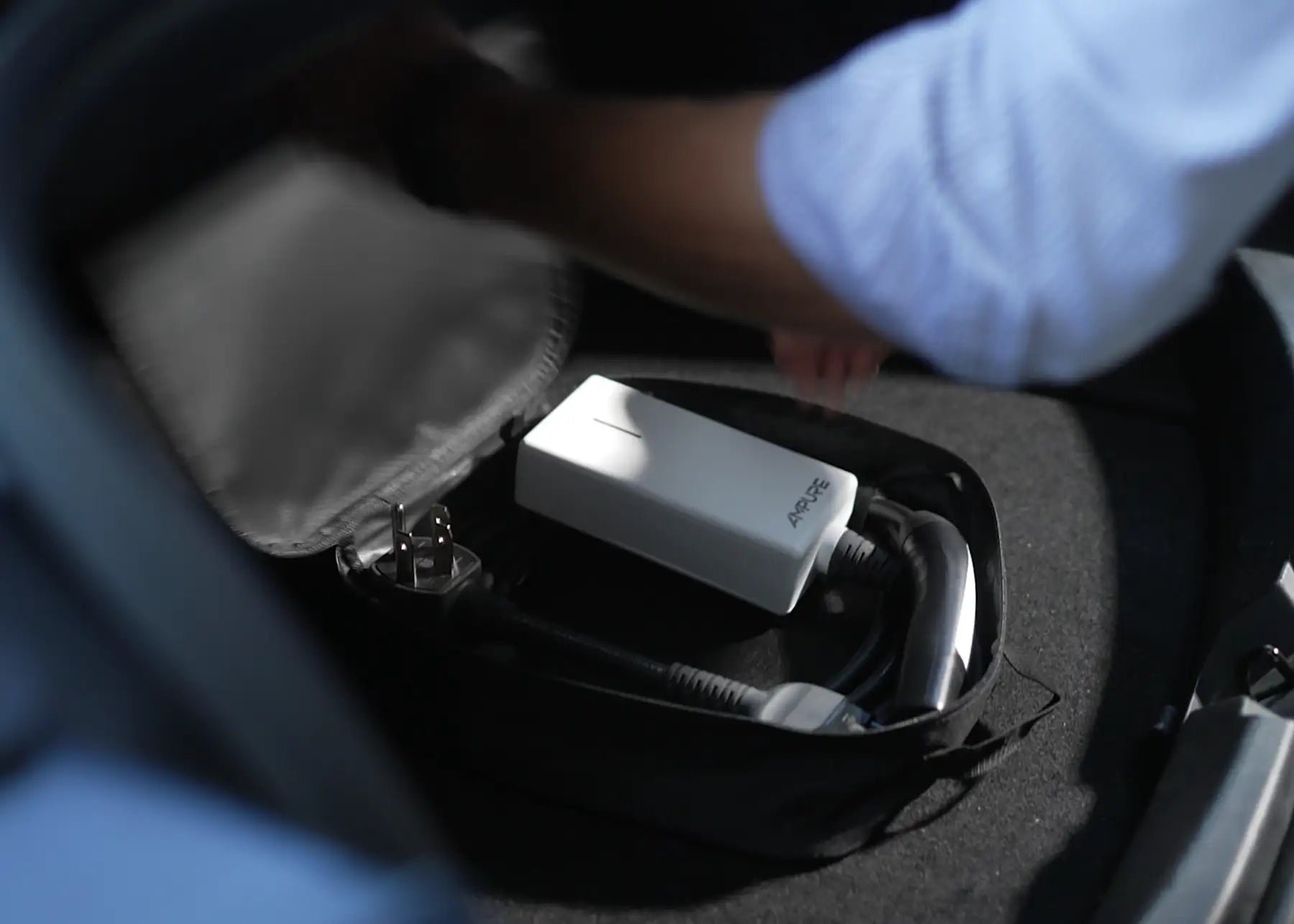 Person opening a car trunk with a white Ampure EV charger in black bag 