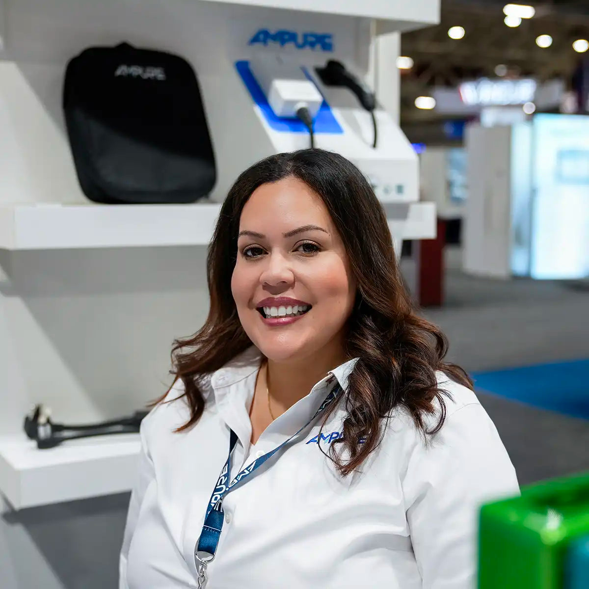 Woman in a white jacket with a lanyard, standing in front of a display with 'AmPure' branding.