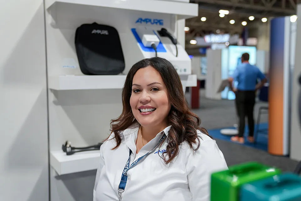 Woman in a white coat standing in front of a display with 'Ampure' branding.