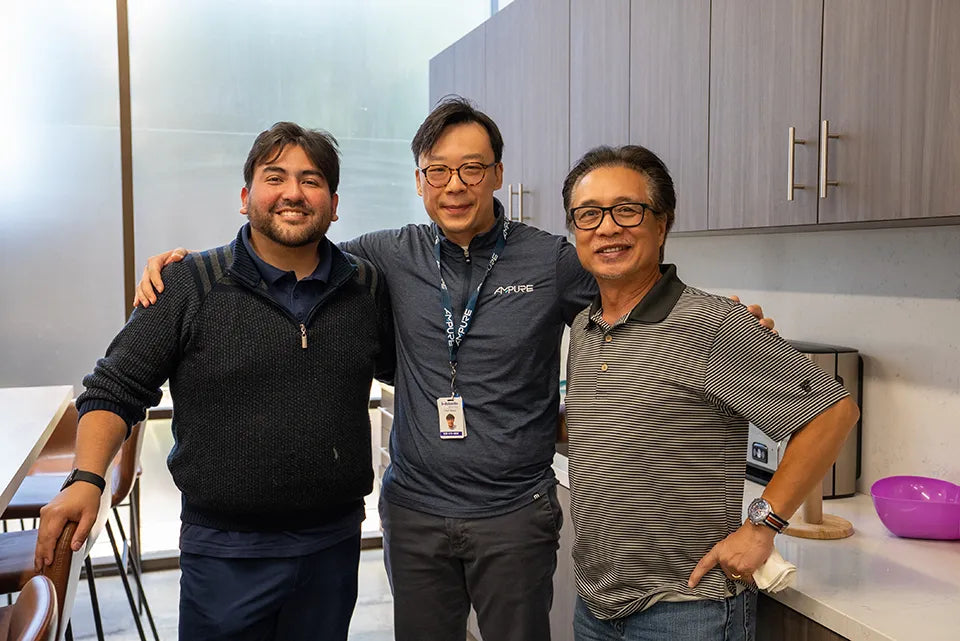 Three men posing together in a kitchen