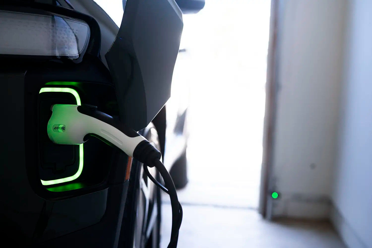 Electric vehicle charging cable plugged into a car's charging port with a blurred background.