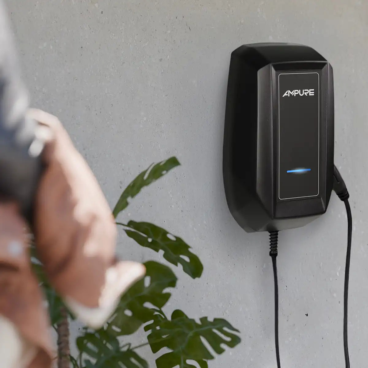 Black Ampure device mounted on a wall with a person and plant in the foreground